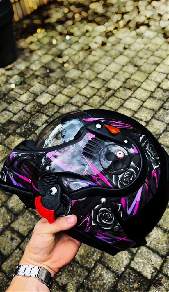 Helmet with a purple and pink kit, held in a hand